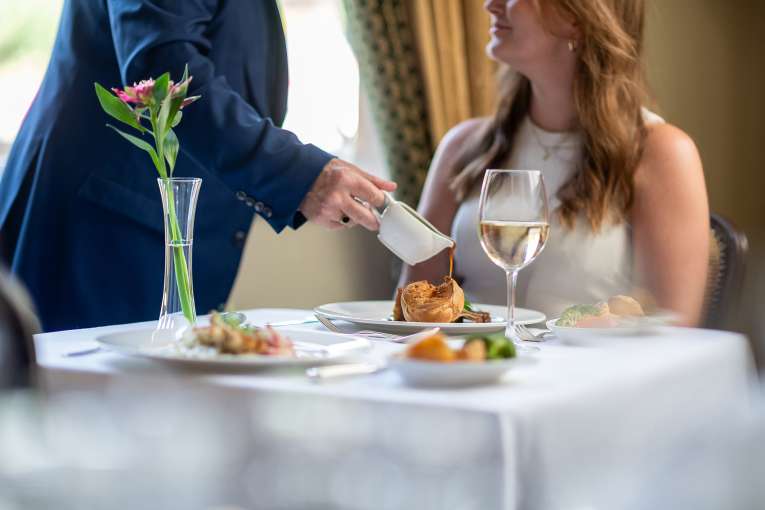 A waitor's hand pouring gravy on a lady's Sunday Roast in The Belmont Restaurant