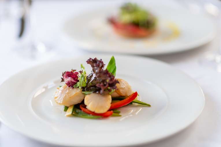 Scallop dish with salad on top on a white plate in The Belmont Restaurant