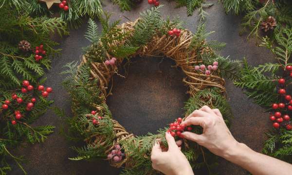 A pair of hands creating a festive wreath
